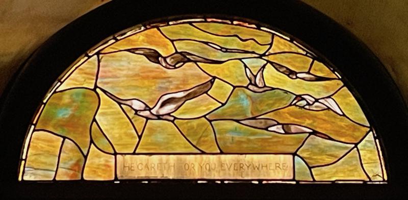 Carrington Commemorative Window:  lunette done in shades of soft amber and green, showing a bird in flight